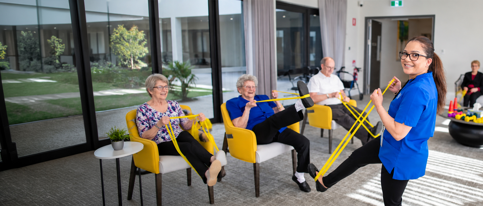Oxa Care staff member leading residents in a seated exercise activity.