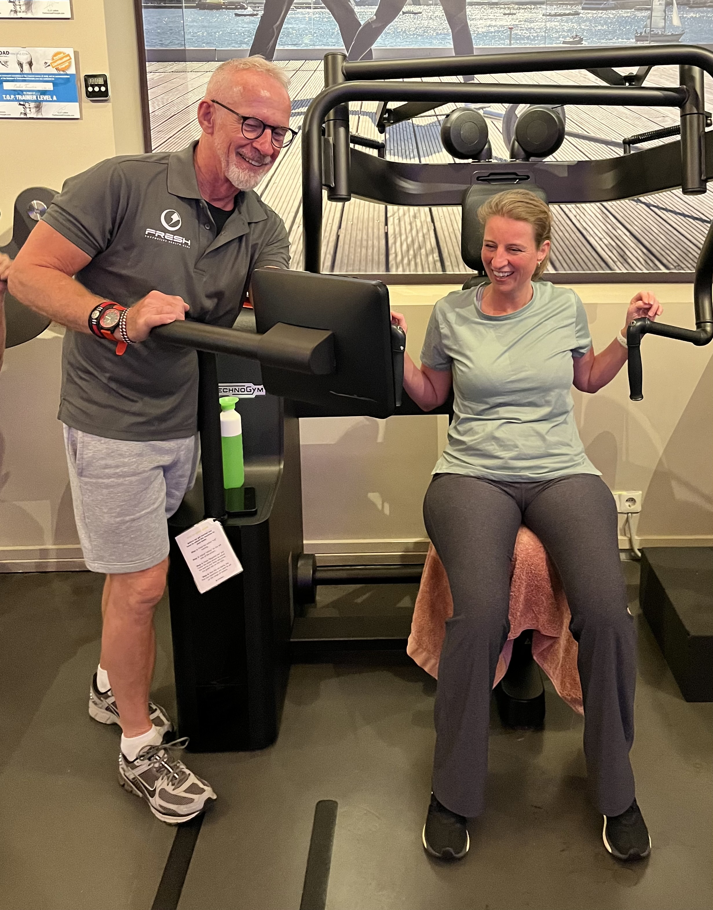 A man helping a woman on the row machine