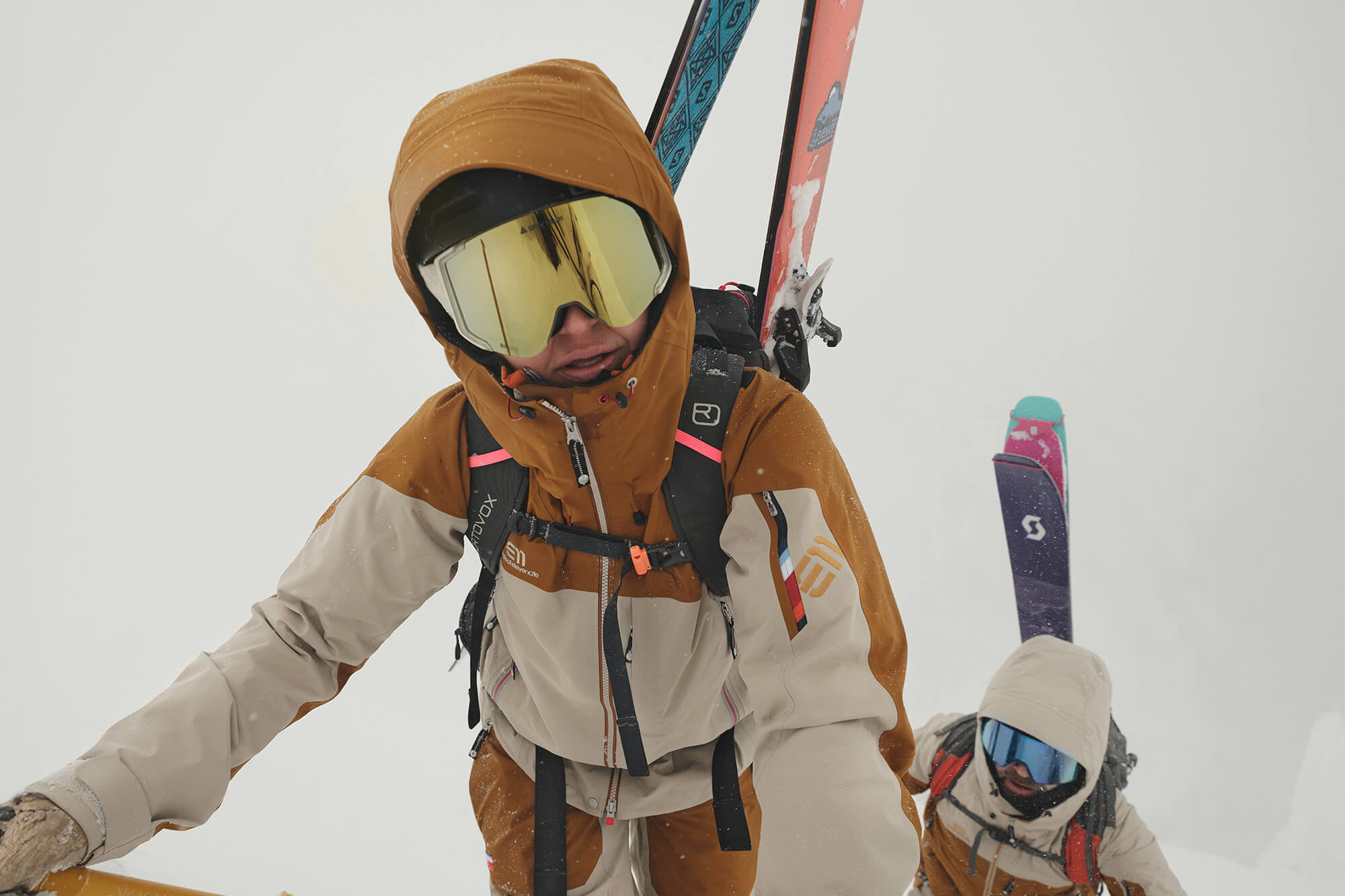 Two skiers wearing Elevenate ski clothing in a snowy mountain landscape