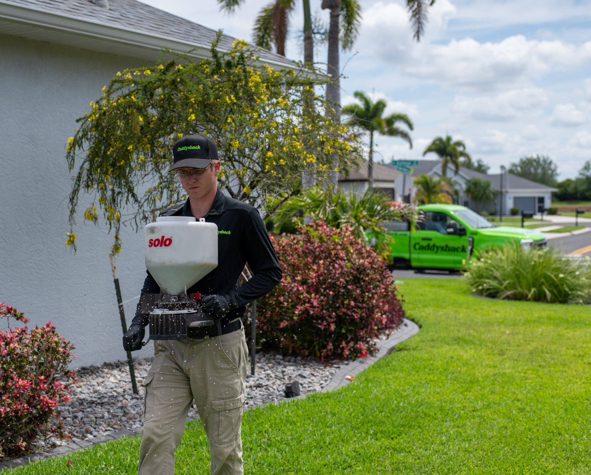 Professional Caddyshack lawn technician applying fertilizer to a Florida lawn
