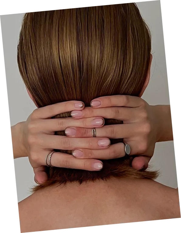 Person's hands with rings gently holding the back of their head with smooth brown hair.