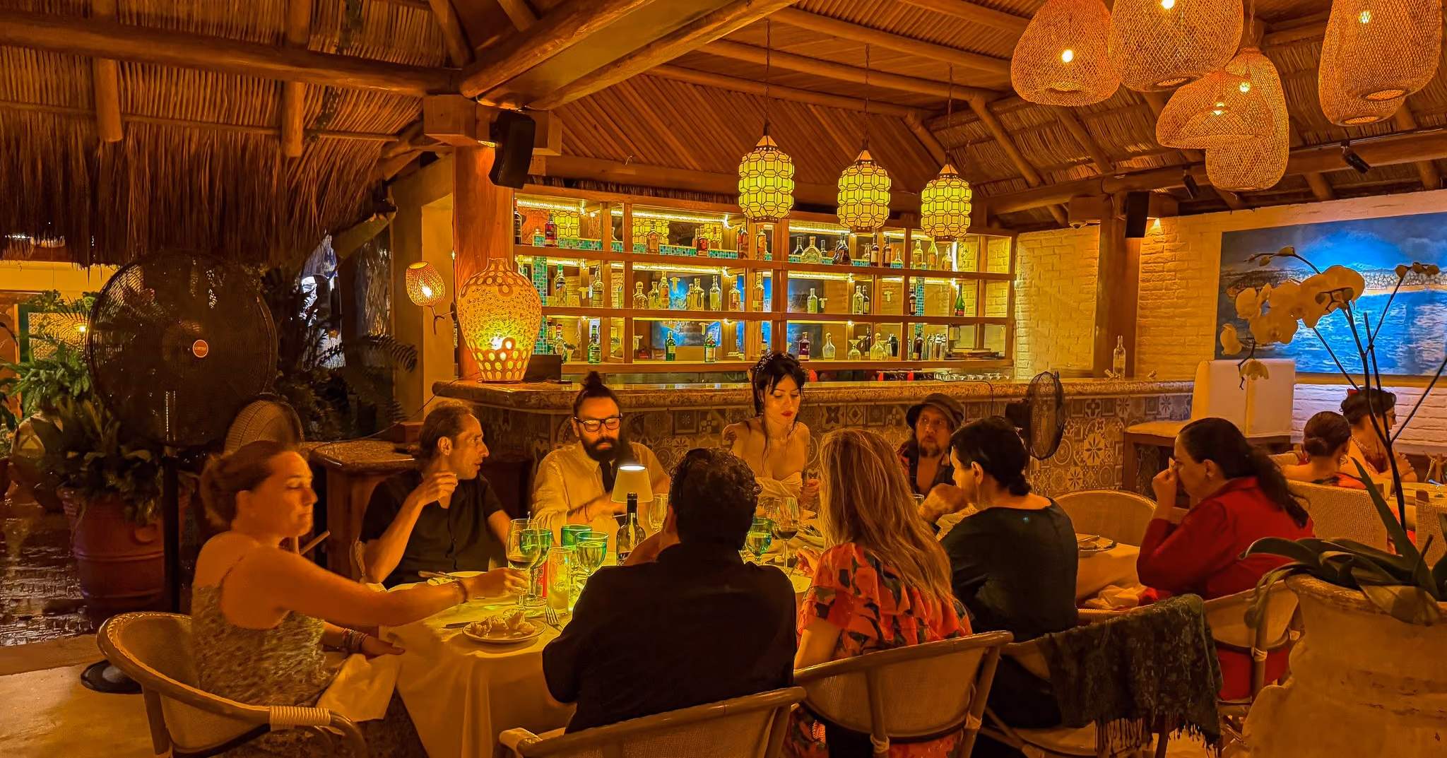 Invitados reunidos en una mesa larga para cenar bajo los farolillos de El Dorado