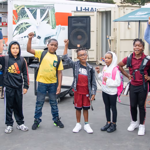 Image of children outside with their arms raised