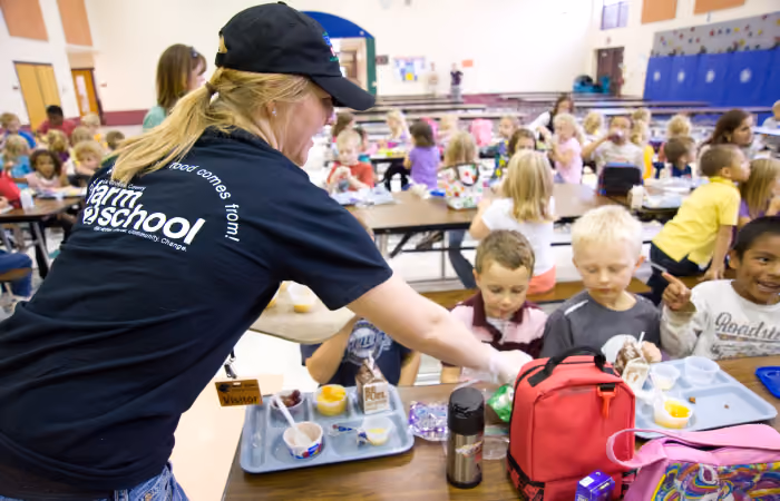 image of a volunteer helping out children with healthy lunches