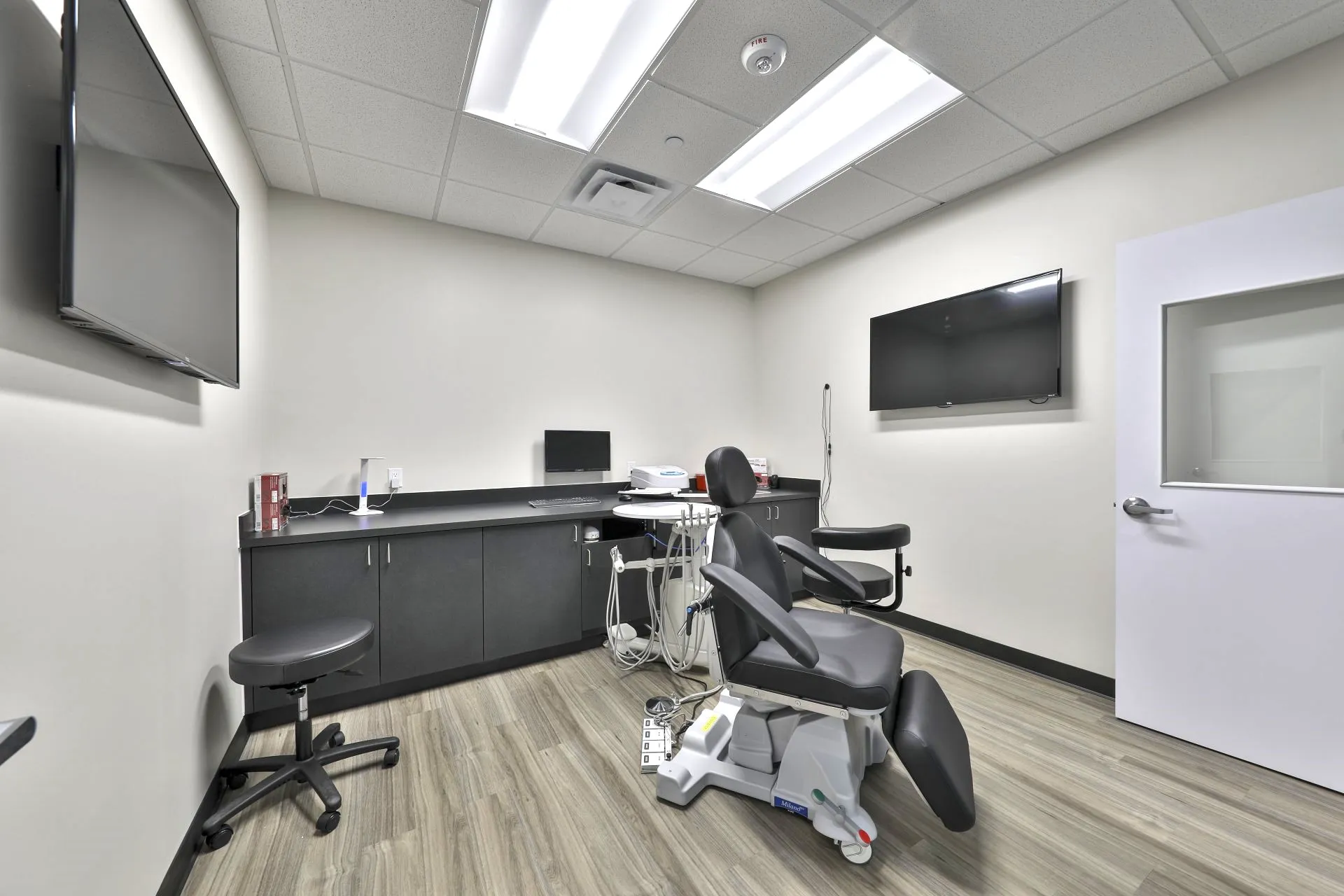 Finished dental operatory with two wall-mounted displays and a chairside charting workstation