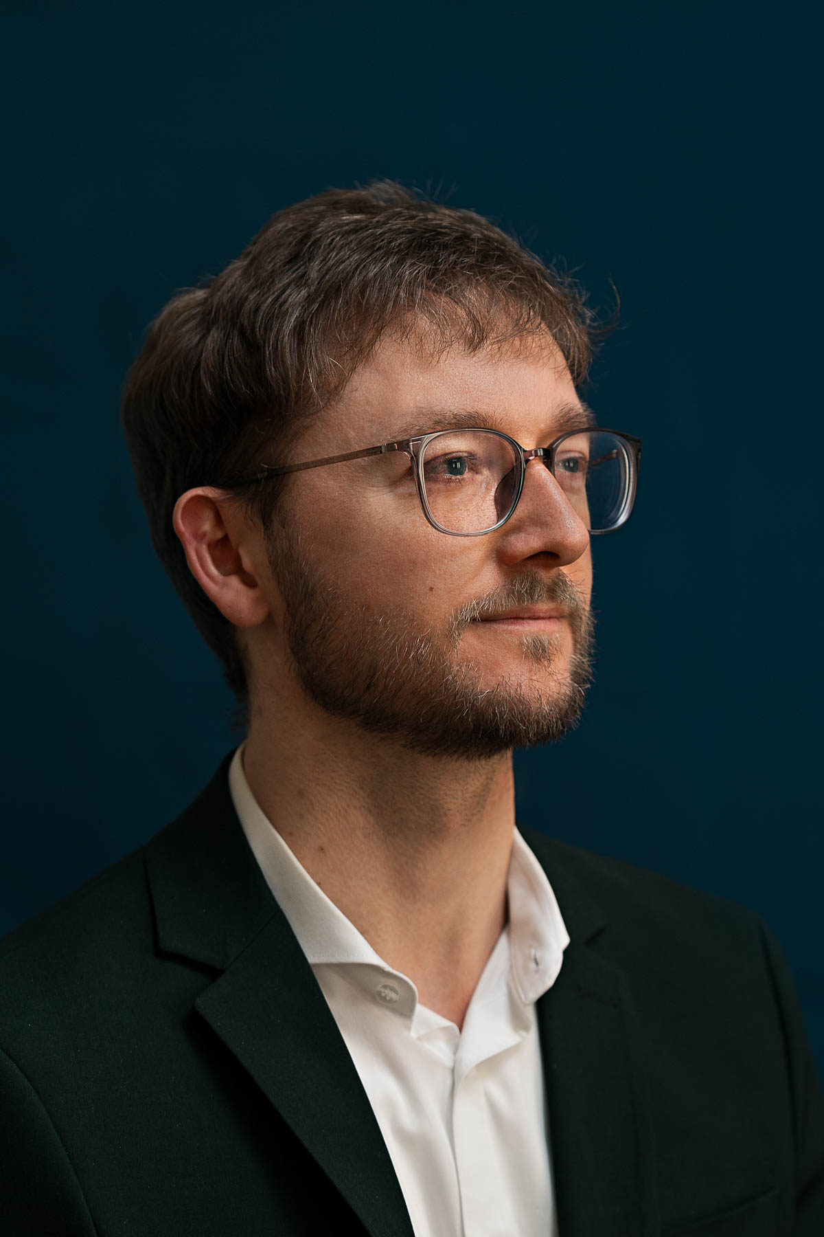 Mann mit blauem Hemd lacht in die Kamera und hält in einer Hand seine Viola und in der anderen einen Bogen