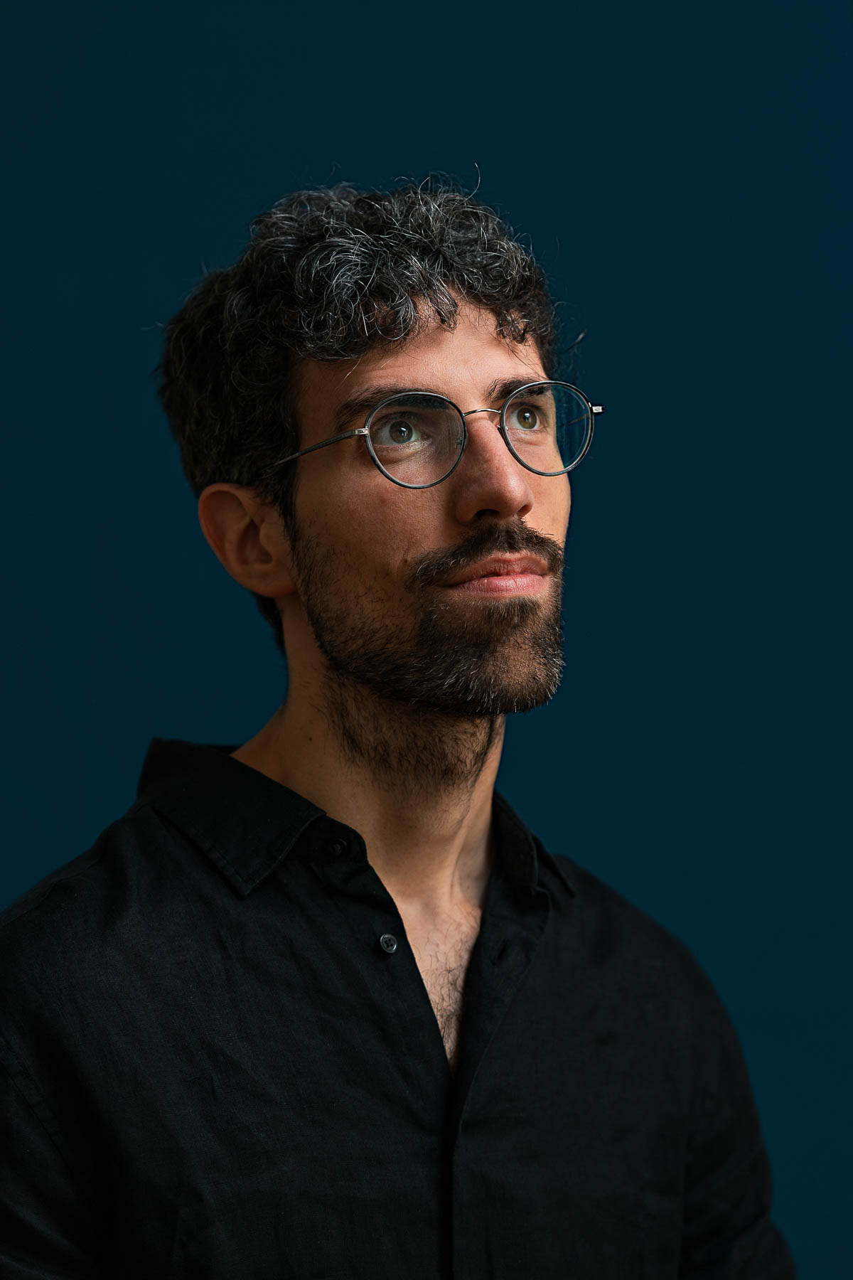 Mann mit Brille und blauem Hemd hält seine Viola in einer Hand und lacht