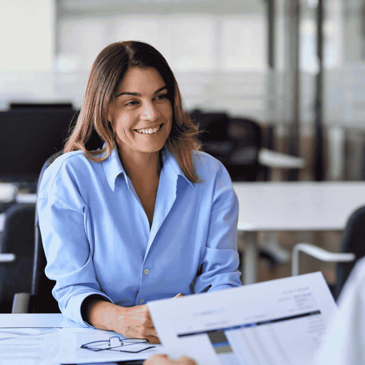 Sales professional discussing training results and performance metrics during a one-on-one business meeting in a modern office.