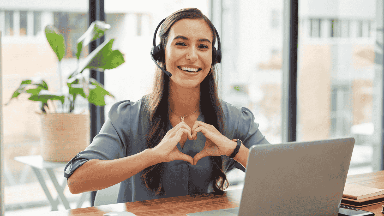 Smiling sales professional making a heart gesture, representing empathy as a driver of customer acquisition and loyalty..