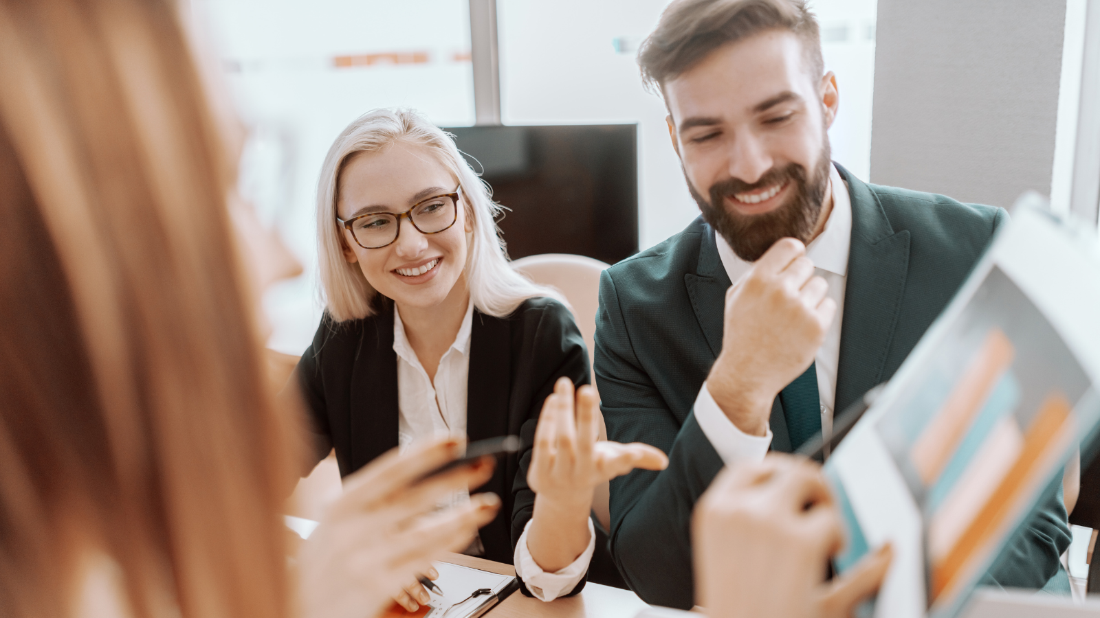 Two salespeople sitting around a desk reviewing reports.