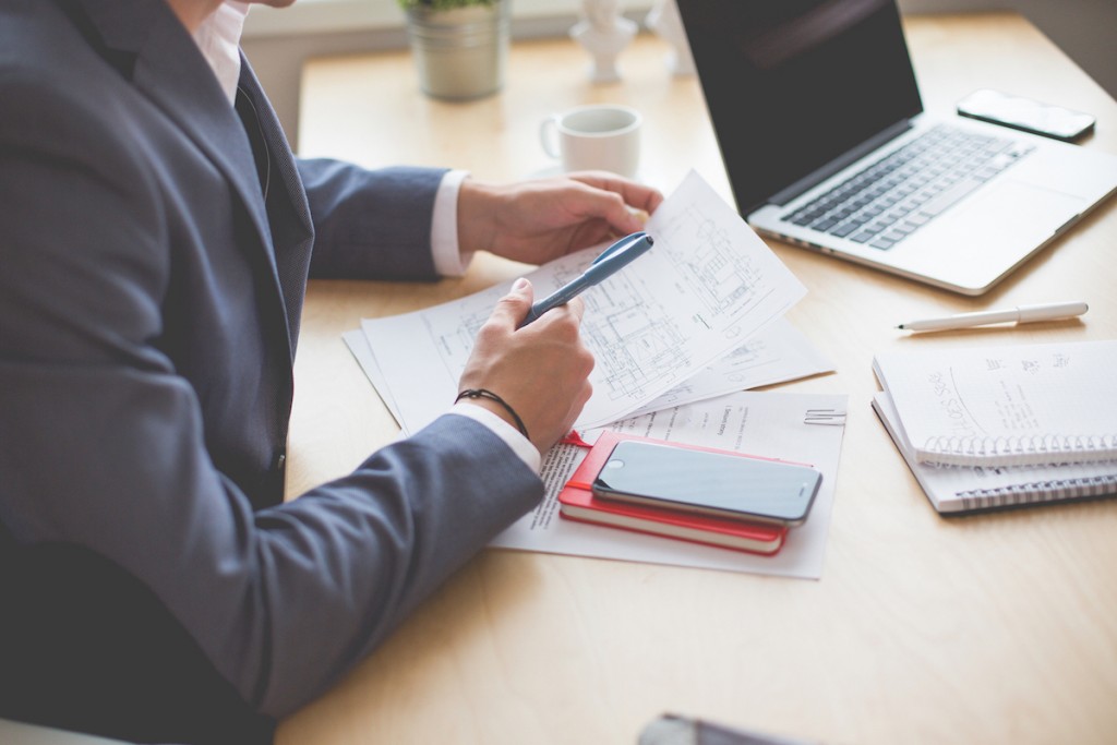 A business man leaned over a desk reviewing a report.