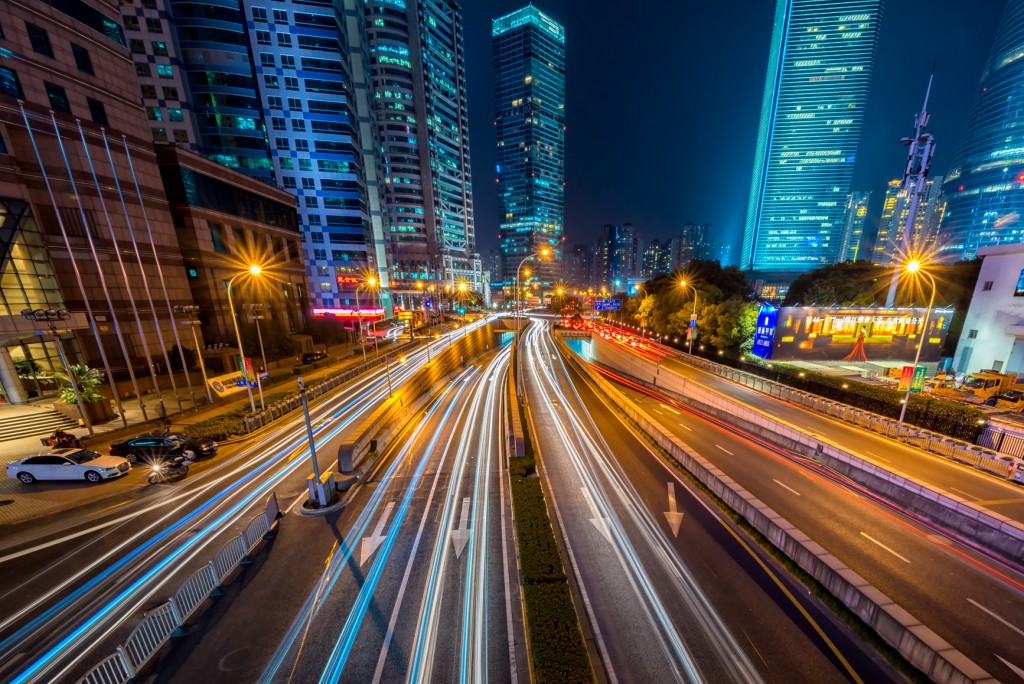 A cityscape at night with cars rushing by.