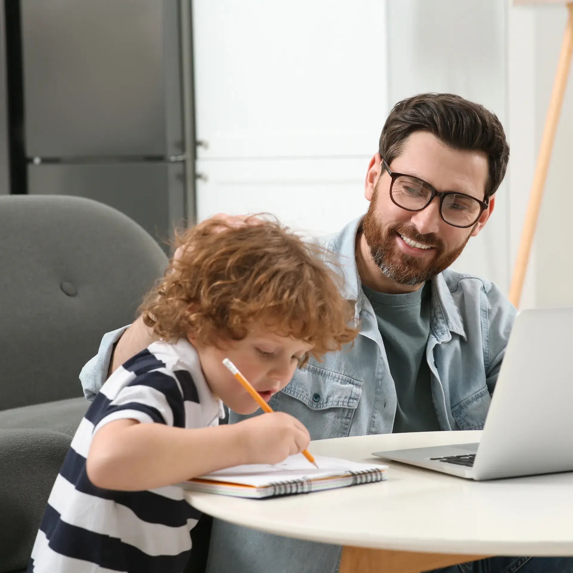 a man sitting at a table with a child and a laptop