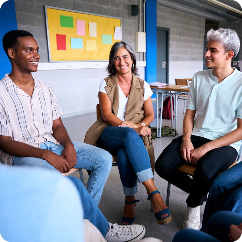 A supportive group session with a diverse group of people, including a facilitator and participants, sitting in a circle and engaging in conversation, emphasizing the importance of a support network for transgender mental health before and after gender-affirming surgery.