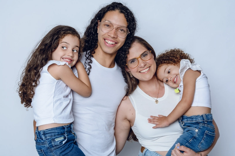A happy family of four standing together and smiling, symbolizing love, support, and the possibility of family building through gender-affirming care.