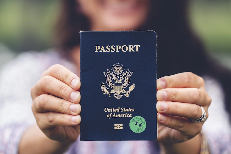 Hands holding a United States passport close to the camera, representing updating legal documents and gender marker changes after gender-affirming surgery.