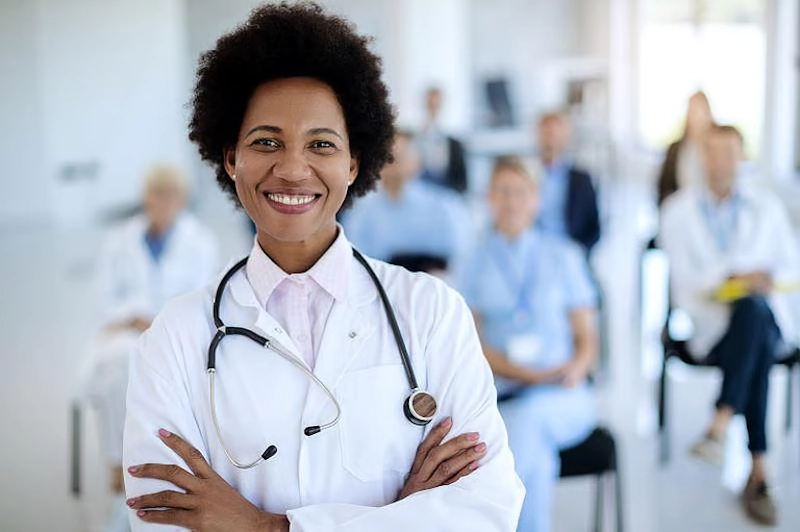 A smiling primary care physician (PCP) in a white lab coat, representing inclusive healthcare and medical support during gender transition.