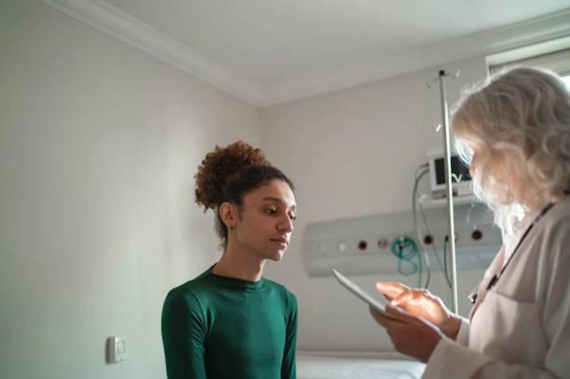 A healthcare provider and patient in a clinical consultation discussing gender-affirming revision surgery options and personalized surgical plans using a digital tablet.