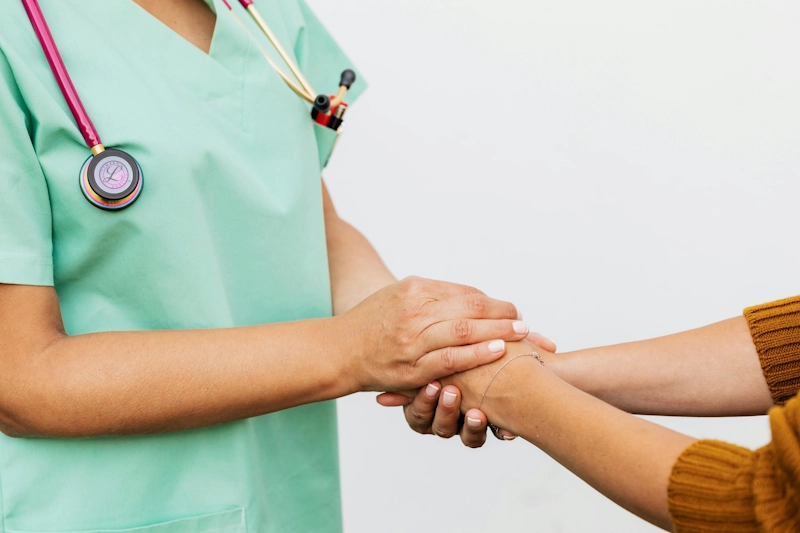 A compassionate healthcare provider holding a patient's hand, symbolizing supportive post-operative care to maintain long-term health outcomes after transgender surgery.