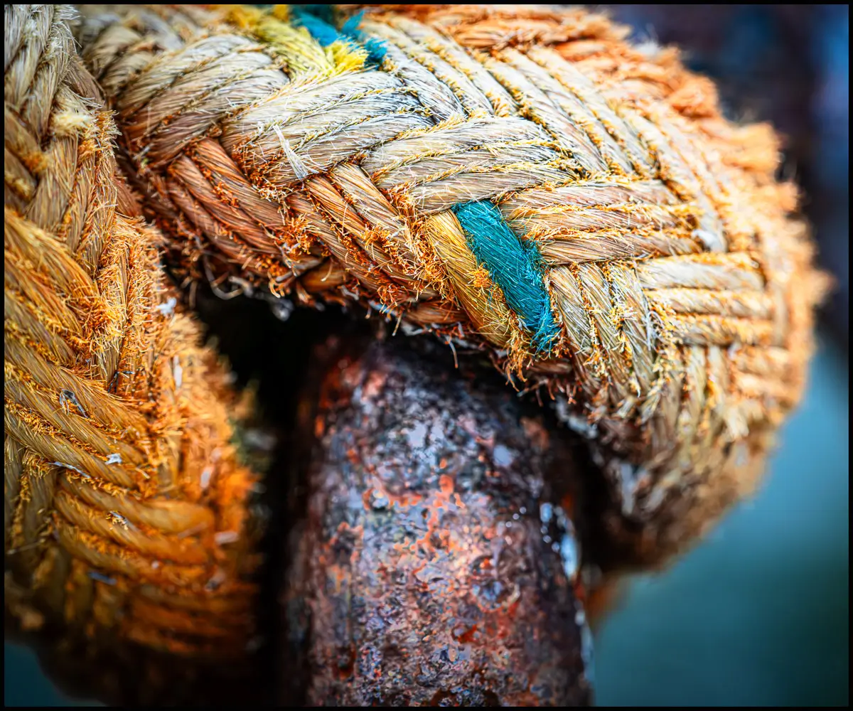 close up of rope knot tied around rusted post