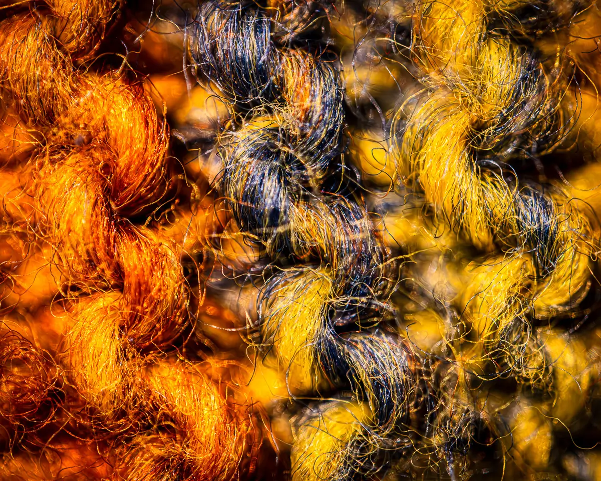 close up of colored yarn showing fraying. orange, yellow, blue