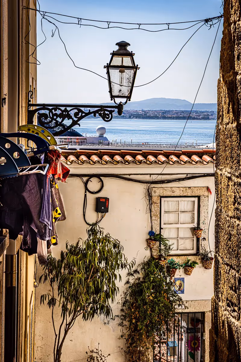 Portugal: hanging laundry over street scene overlooking a lamplight and water