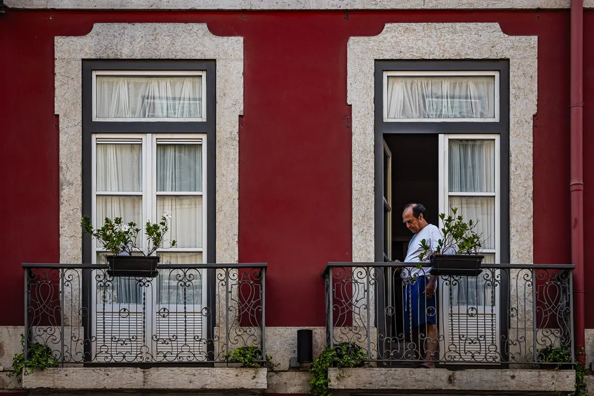 Portugal man on balcony of red home