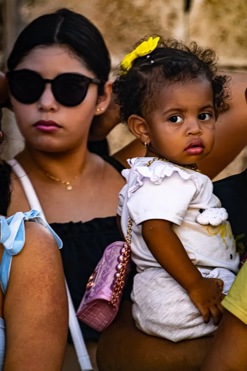 Colombia Independence Day Parade: mother holding young girl with ribbon and pink purse