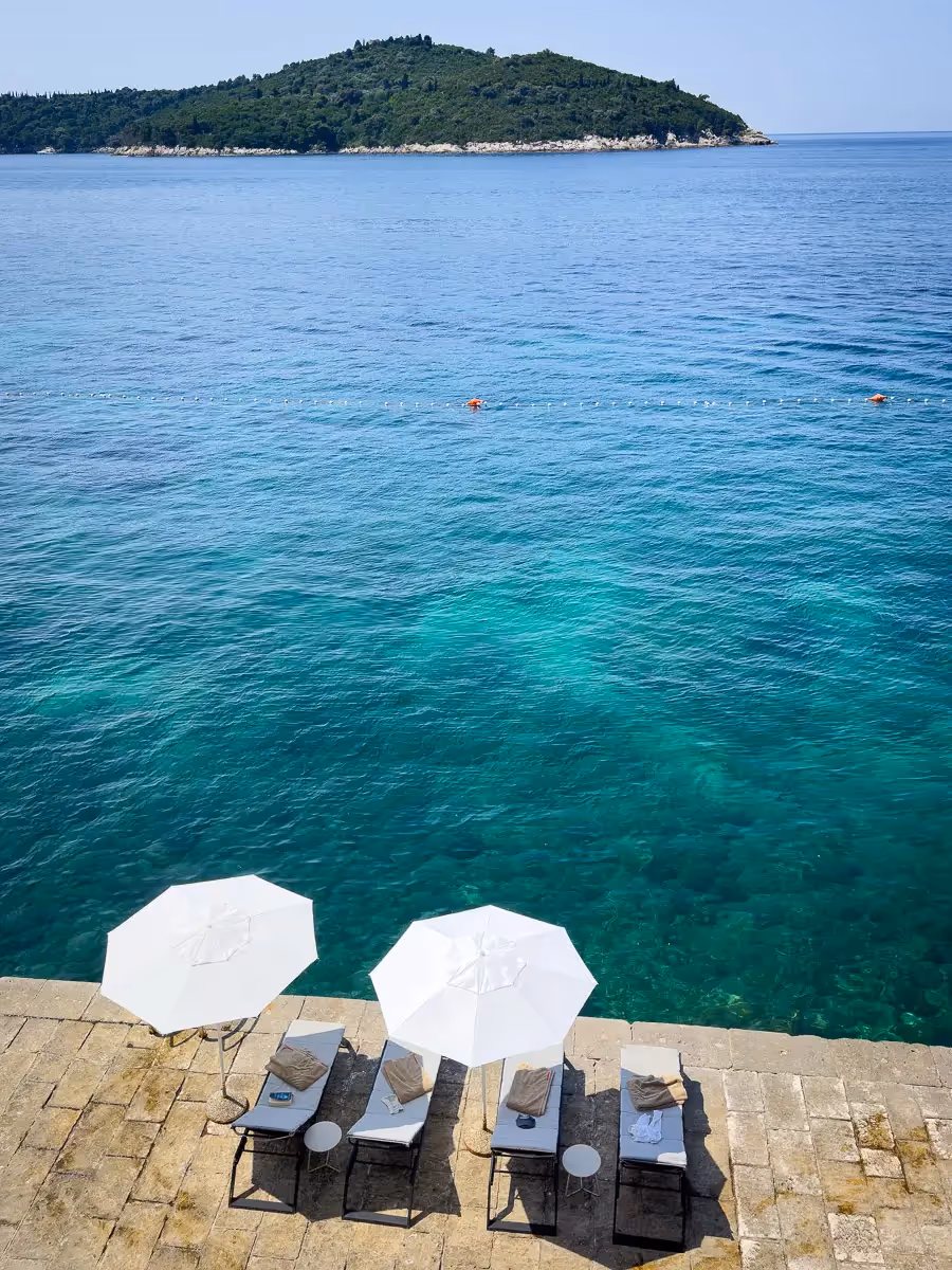 Croatia, paradise awaits with 2 chaise lounges outfitted with towels and umbrellas, overlooking the crystal clear blue-green water
