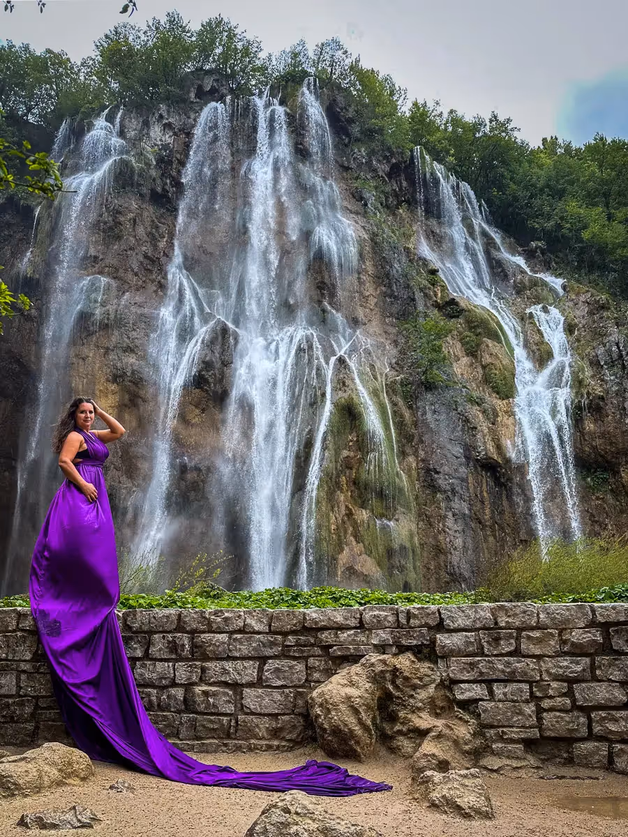 Woman in purple dress modeling in front of a waterfall at Plitvice National Park in Croatia