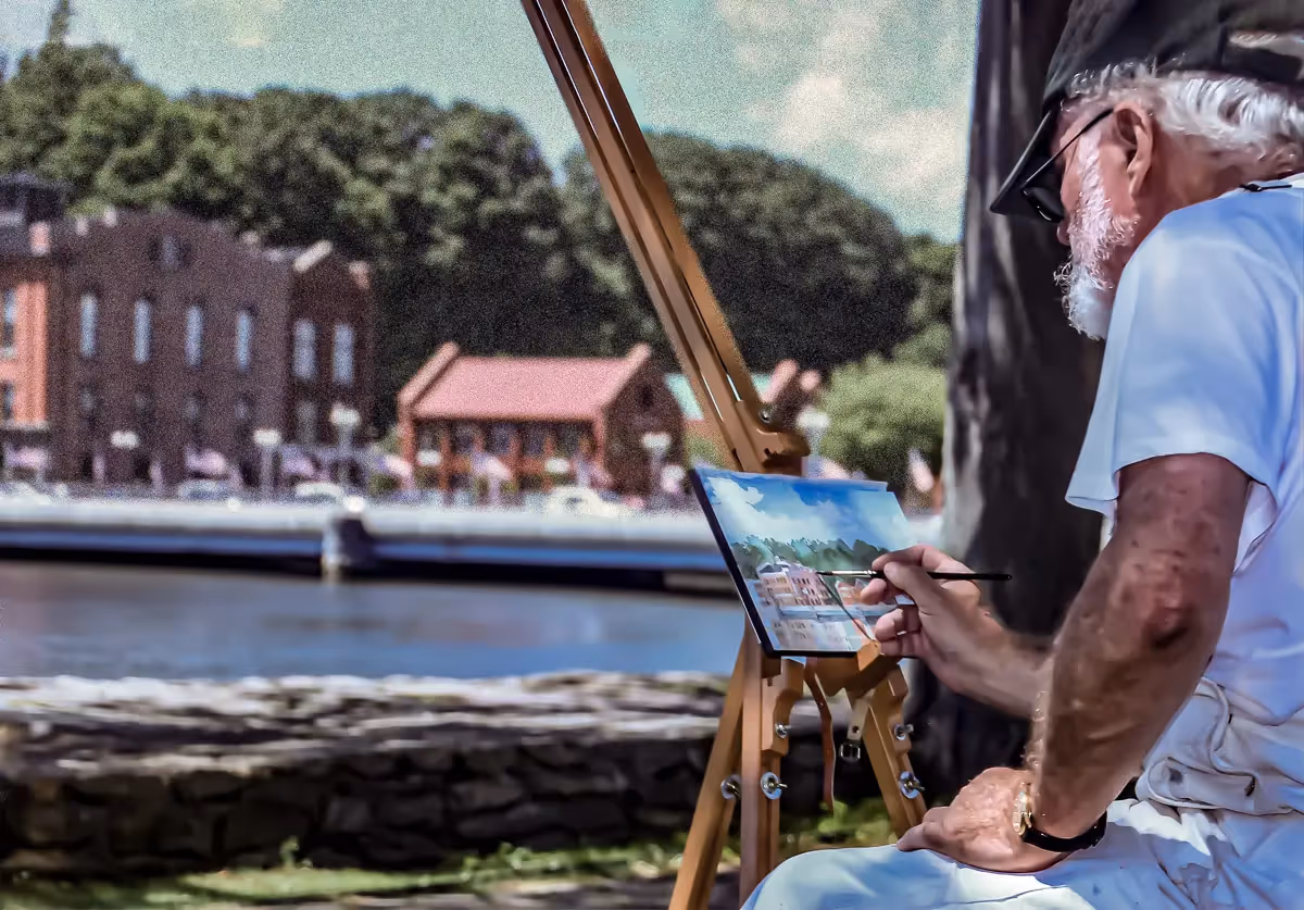 Painter painting iconic building across the river in Westport CT