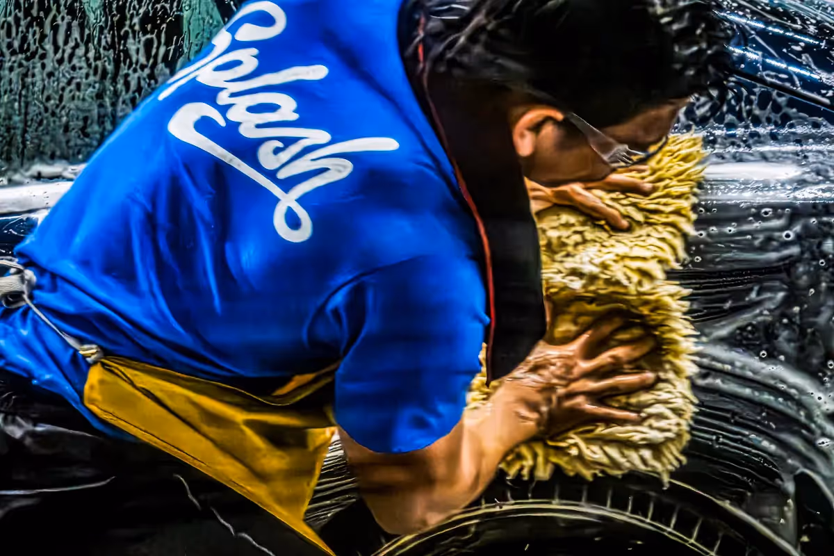 Scrubber at a car wash with rags in both hands