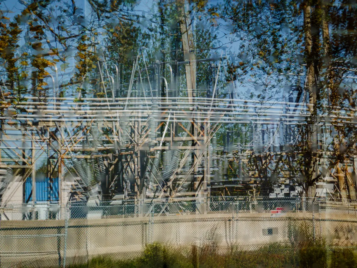 Manresa Island Power Plant: reflection in window of trees with electrical plant in the background