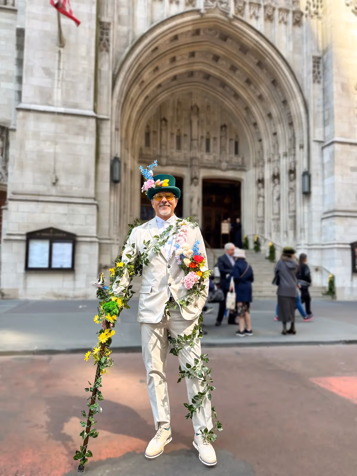 2024 Easter Bonnet Parade, NYC:  man in white suit covered in green ivy vines with a vine-wrapped can and top hat