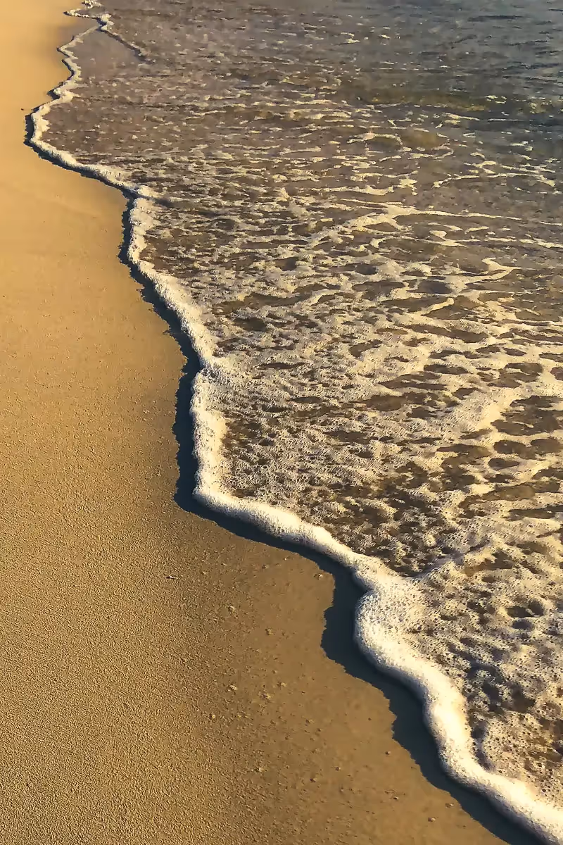 smooth beach showing an abstract line of foam at the waters edge