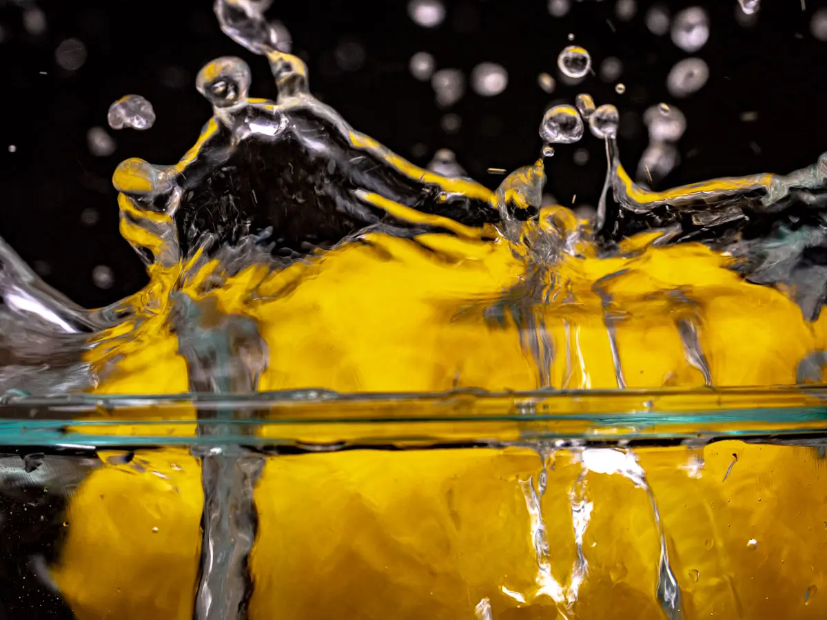 Water splashing out of glass bowl from lemon dropping in