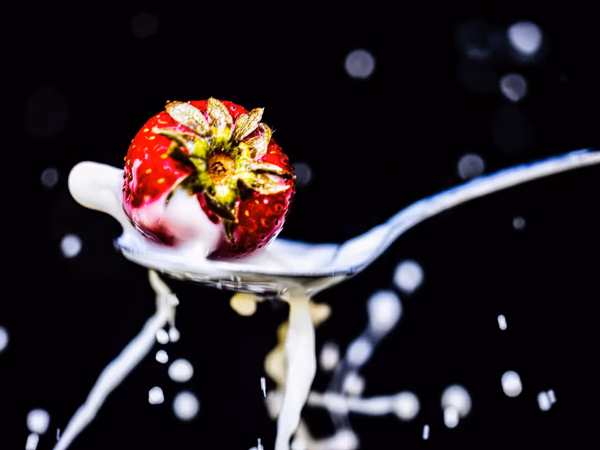 milk splatter in spoon from splashing strawberry