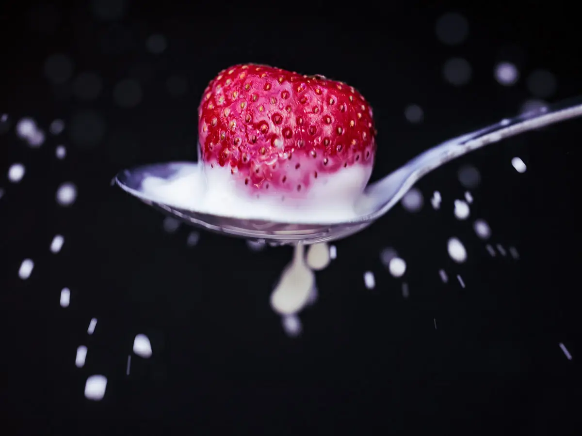 milk splatter in spoon from splashing strawberry