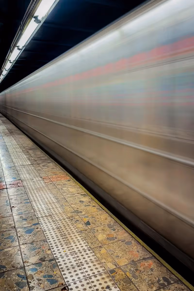 NYC subway train zooming by and converging with the station ceiling lights