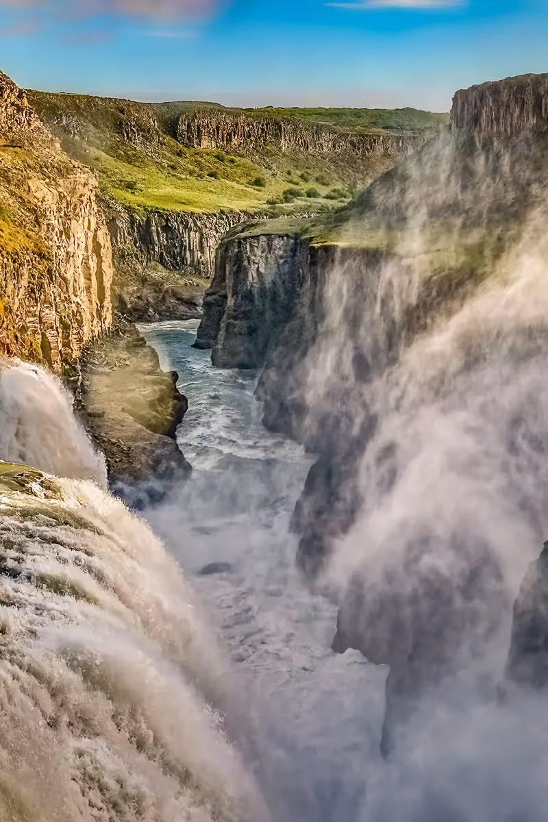 Powerful waterfalls on both sides of a narrow cliff lined river that flows into the distance 