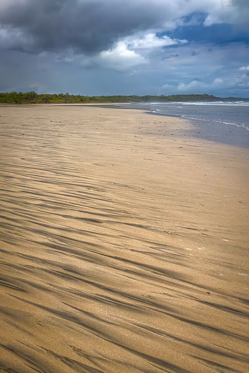 Costa Rica beach expanse with the black patterns from eroded volcanic material like basalt and, lava fragments,   