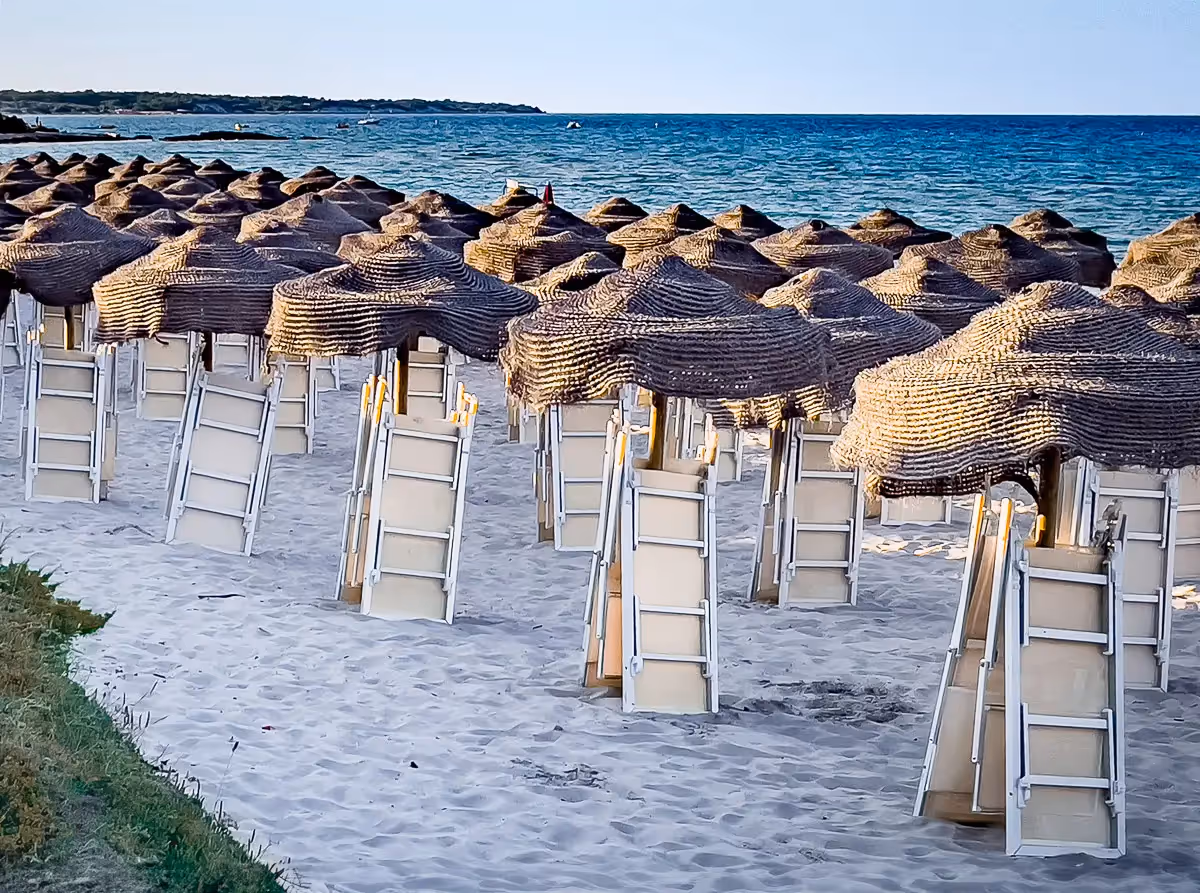 Beach chairs folded up under the wicker umbrellas at the end of the day on a beach in Italy