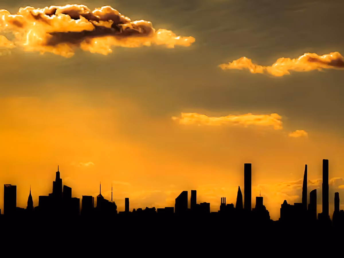 Silhouette of the New York City skyline under a yellow sunset sky