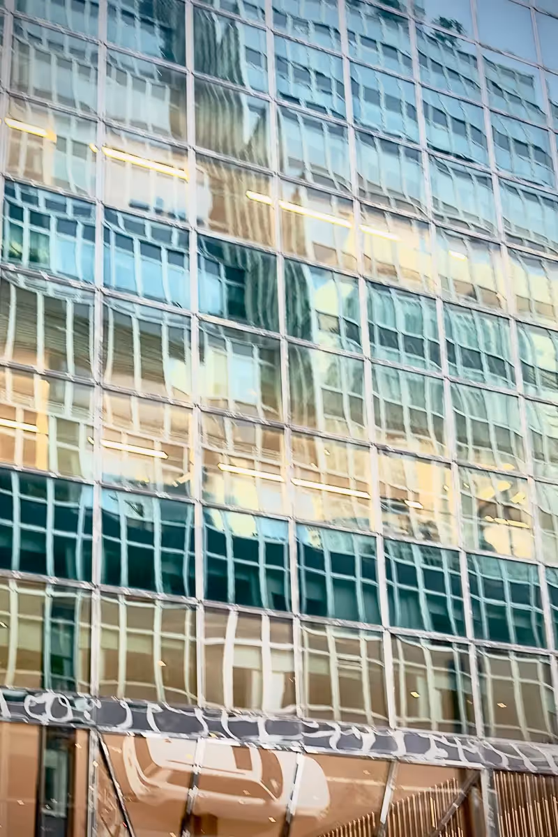 New York City glass building with reflections of a car and the street making look like the building is wavering