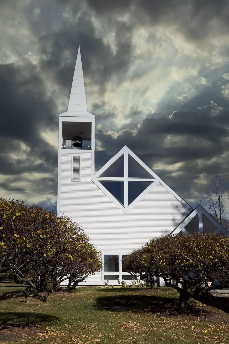 stark white church with a dramatic cloudy sky behind it
