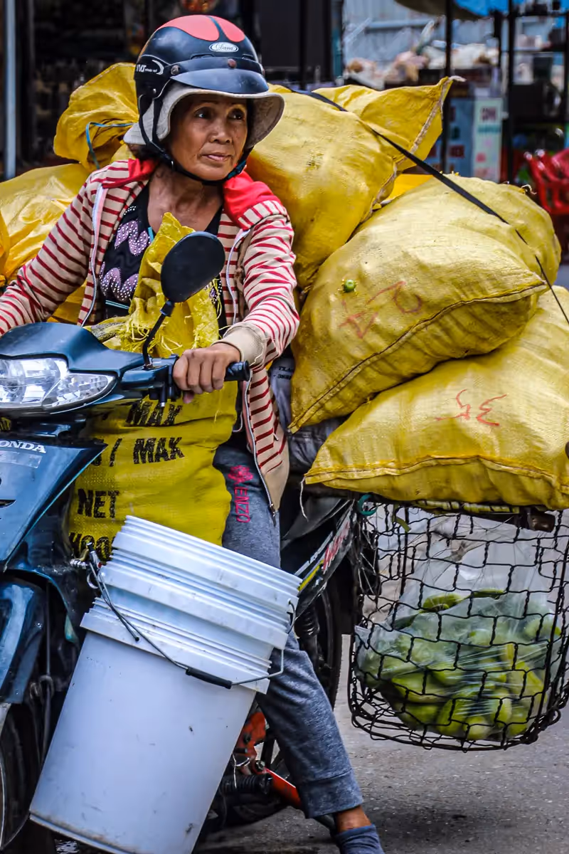 Vietnam: woman on moped carrying an impossible number of bags
