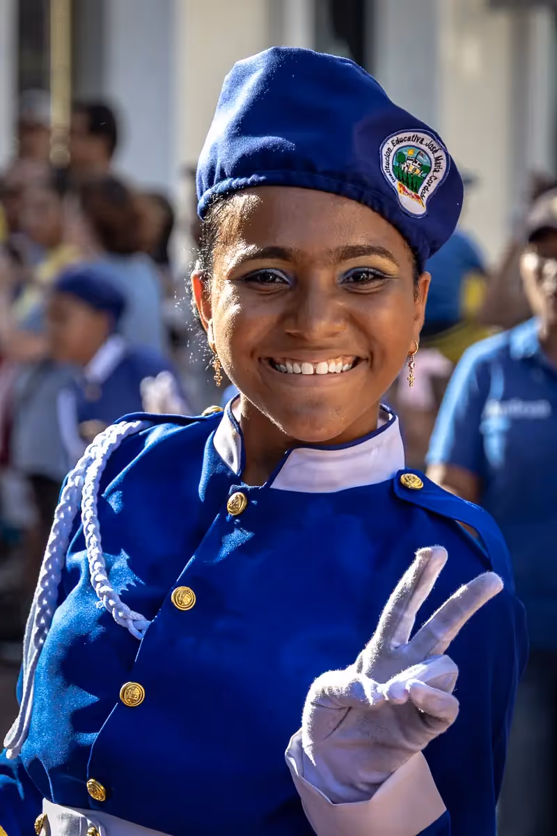 Colombia Independence Day Parade: girl with big smile showing me the peace sign with her white clove covered hand