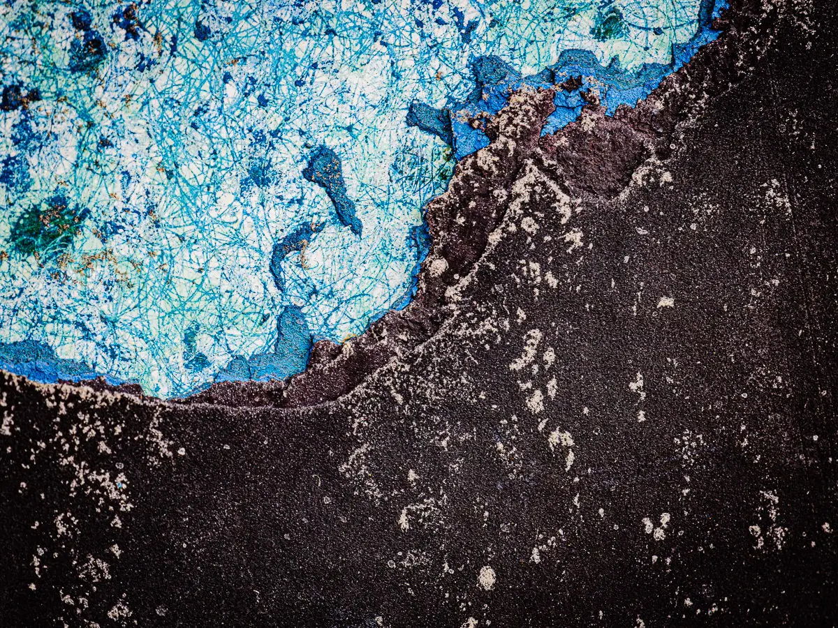 Patterns of rust and barnacles on the hull of a boat out of water.