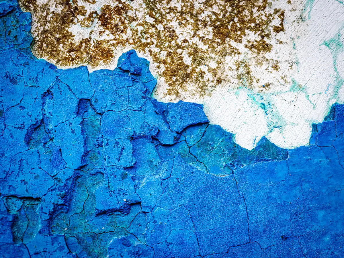 Patterns of rust and barnacles on the hull of a boat out of water.