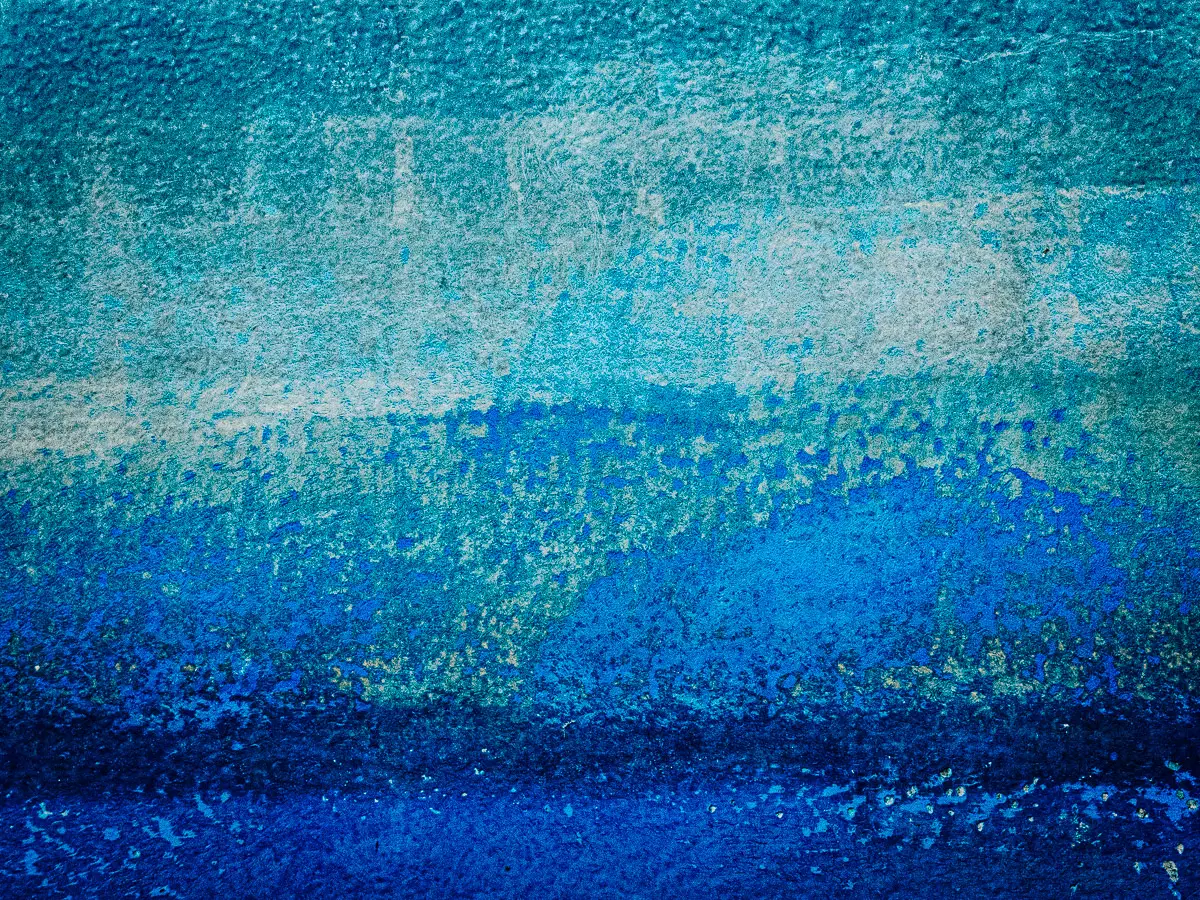 Patterns of rust and barnacles on the hull of a boat out of water.